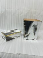 A luxury white and black marble-patterned tissue box holder and matching wastebasket with elegant gold trim, displayed on a wooden table.A luxury white and black marble-patterned tissue box holder and matching wastebasket with elegant gold trim, displayed on a wooden table.