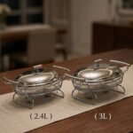 Two Paramount Series stainless steel oval food warmers in 2.4L and 3L sizes on a table runner, featuring glass bowls and polished metal lids.