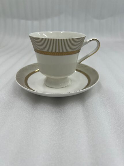 A premium white Super Bone China tea cup and saucer set featuring gold vertical stripes and a gold laurel wreath pattern on a dark wooden table