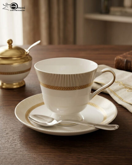 A premium white Super Bone China tea cup and saucer set featuring gold vertical stripes and a gold laurel wreath pattern on a dark wooden table