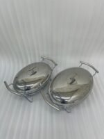Two Paramount Series stainless steel oval food warmers in 2.4L and 3L sizes on a table runner, featuring glass bowls and polished metal lids.