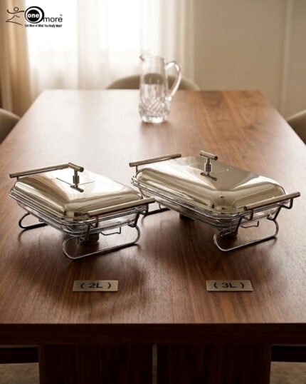 Two Paramount Series stainless steel food warmers in 2L and 3L sizes on a wooden table, featuring glass basins and polished metal lids.