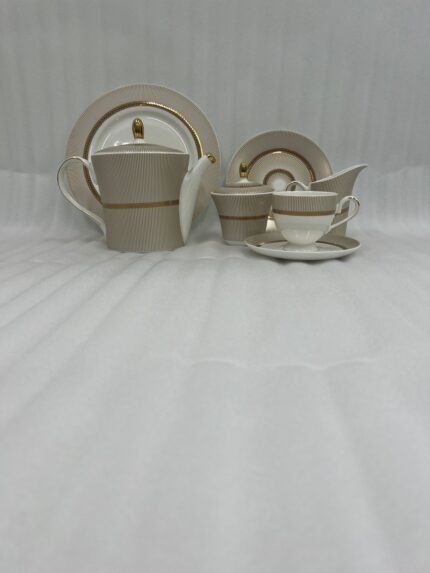 A premium Super Bone China tea set featuring a teapot, sugar bowl, creamer, and cups and saucers with a tan pinstripe pattern and gold-rimmed borders, arranged on a wooden table outdoors with avocado toast on a plate.