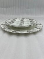Stacked 18-piece super bone china plate set with grey floral patterns, including rice plates, deep plates, and quarter plates on a wooden dining table.