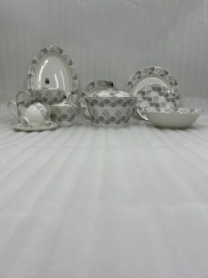 Elegant 61-piece white Super Bone China dinner set with grey floral patterns, including plates, bowls, a teapot, and a lidded casserole dish, displayed on a wooden table.