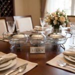 A Paramount Series 3-in-1 stainless steel food warmer buffet server with three 1.5L glass dishes and polished metal lids, featuring integrated buffet burner holders on a set dining table.