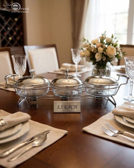 A Paramount Series 3-in-1 stainless steel food warmer buffet server with three 1.5L glass dishes and polished metal lids, featuring integrated buffet burner holders on a set dining table.