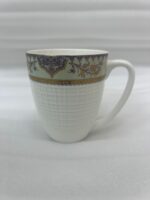 Enjoy the perfect blend of elegance and comfort with this premium bone china mug set. Featuring an intricate, vintage-inspired filigree border in deep purple and gold tones, these mugs bring a touch of royalty to your daily tea or coffee rituals. The lower half of the mug boasts a sophisticated textured grid pattern, providing a modern tactile feel and a secure grip. Crafted for those who appreciate fine craftsmanship, this set is ideal for cozy rainy mornings on the balcony or hosting guests with style. Key Features Premium Bone China: Lightweight yet durable with a smooth, translucent finish. Intricate Artistry: Beautifully detailed ethnic motifs and gold accents for a luxury aesthetic. Ergonomic Design: Large, comfortable handle and a textured body for an enhanced grip. Versatile Use: Perfect for hot tea, coffee, lattes, or hot chocolate. Capacity: Standard size, ideal for a generous serving of your favorite beverage