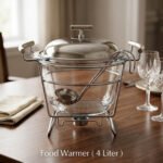 Paramount Series 4-liter glass food warmer with a stainless steel stand, lid, and ladle, featuring a buffet burner holder on a wooden dining table.v
