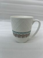 A set of white bone china mugs featuring a diamond-embossed top half and a decorative gold and teal traditional pattern at the bottom, filled with steaming tea on a wooden desk