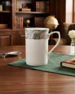 Set of two white bone china mugs from 3.jpg on a wooden table with a green placemat; one tall mug and one short mug, both featuring a grey marble pattern band and silver trim against a library background with cinematic lighting