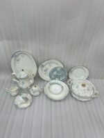 A complete super bone china dinner set featuring delicate blue and grey floral patterns with silver rims, arranged on a wooden table.
