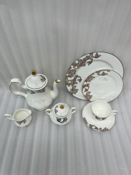 Elegant super bone china tea set featuring a teapot, teacup, plates, cream pitcher, and sugar bowl with a brown vintage baroque pattern and gold rims, displayed on a wooden table.