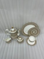 A premium super bone china tea set featuring a teapot, teacup and saucer, creamer, and sugar bowl with elegant beige striped patterns and luxury gold accents on a wooden table.