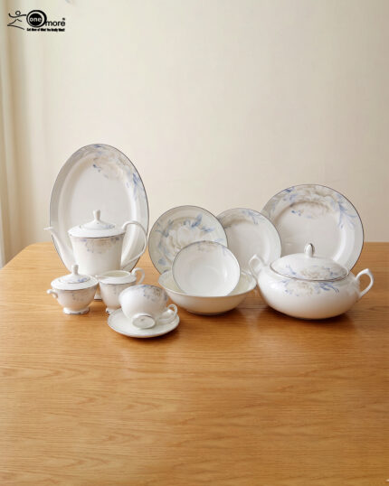 A comprehensive 61-piece super bone china dinner set for an 8-person serving, displayed on a wooden table against a neutral background. The white ceramic tableware features a delicate light blue and grey floral pattern with thin silver rims. The set includes a large oval platter, dinner plates, side plates, soup bowls, a covered casserole dish, a teapot, a creamer, a sugar bowl, and tea cups with saucers.