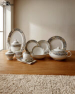 An elegant 61-piece premium super bone china dinner set with grey and gold marbled rims displayed on a warm wooden tabletop, featuring luxury plates, bowls, a covered tureen, and a teapot setup