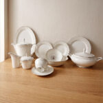 OneMore 61-piece premium super bone china dinner set for an 8-person serving, featuring elegant silver borders, displayed on a light wooden table against a minimalist neutral wall.