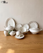 Elegant 61-piece super bone china dinner set by OneMore with an intricate silver lace border design, beautifully arranged on a wooden table against a plain background, including plates, bowls, a teapot, and a soup tureen