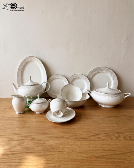 Elegant 61-piece super bone china dinner set by OneMore with an intricate silver lace border design, beautifully arranged on a wooden table against a plain background, including plates, bowls, a teapot, and a soup tureen