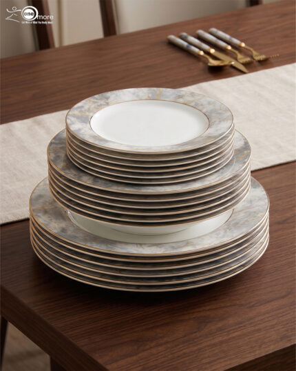 A stacked 18-piece super bone china dinnerware set featuring a modern grey and gold marble pattern with elegant gold rims, neatly displayed on a wooden dining table alongside luxury cutlery.