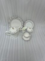 A 24-piece luxury porcelain tea set featuring a delicate blue floral pattern, gold accents, and striped borders, arranged elegantly on a linen runner.