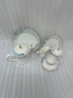 A 24-piece luxury porcelain tea set featuring a white base, marble-patterned rims in blue and grey, and delicate gold detailing, arranged on a wooden table.