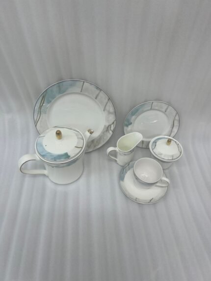 A 24-piece luxury porcelain tea set featuring a white base, marble-patterned rims in blue and grey, and delicate gold detailing, arranged on a wooden table.