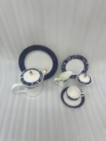A 24-piece luxury tea set featuring white porcelain with deep blue floral patterns and gold-rimmed accents, including a teapot, cups, saucers, and plates.