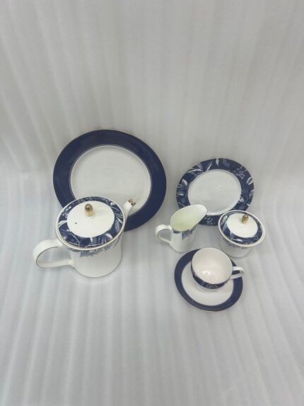 A 24-piece luxury tea set featuring white porcelain with deep blue floral patterns and gold-rimmed accents, including a teapot, cups, saucers, and plates.
