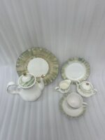 A 24-piece luxury porcelain tea set featuring white dishes with soft green, brush-stroke patterned edges and delicate gold rims, displayed on a wooden surface.