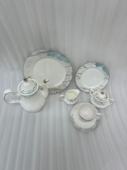 A luxurious 24-piece porcelain tea set featuring white ceramic with blue marble patterns and gold trim, displayed on a marble surface.