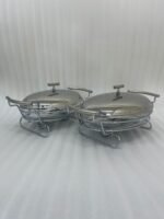 Two Paramount Series stainless steel oval food warmers in 2.4L and 3L sizes on a table runner, featuring glass bowls and polished metal lids.