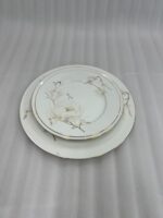 A stacked 18-piece super bone china plate set from Onemore Crockery featuring floral patterns and gold rims, displayed on a wooden table.