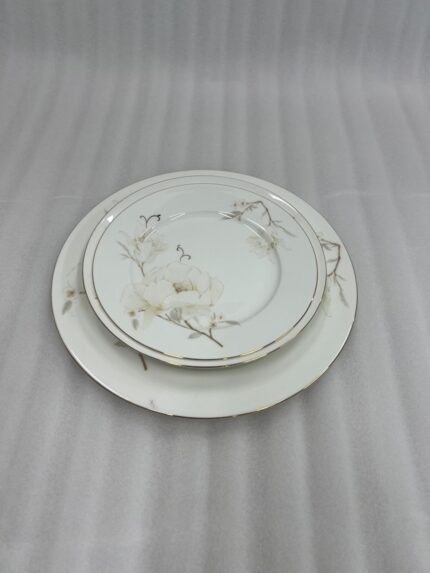 A stacked 18-piece super bone china plate set from Onemore Crockery featuring floral patterns and gold rims, displayed on a wooden table.