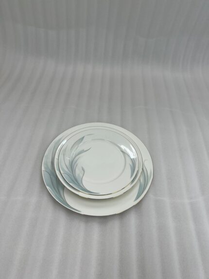 A stacked 18-piece white super bone china plate set on a wooden dining table, featuring 6 rice plates, 6 deep plates, and 6 quarter plates with a subtle design