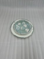 A stack of 18 super bone china plates featuring a sage green and white floral design, including rice plates, deep plates, and quarter plates, displayed on a white damask runner