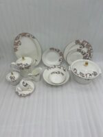 A luxury 61-piece Super Bone China dinner set with an intricate brown scroll pattern and gold accents, elegantly arranged for an 8-person serving on a white tablecloth under a crystal chandelier
