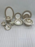 A premium 61-piece Super Bone dinner set by OneMore Crockery featuring cream-colored plates with gold-rimmed textured borders, including a teapot, cups, serving bowls, and platters arranged on a dark wooden table