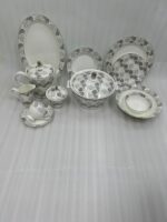 Elegant 61-piece white Super Bone China dinner set with grey floral patterns, including plates, bowls, a teapot, and a lidded casserole dish, displayed on a wooden table.