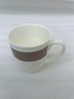 A set of six elegant white bone china mugs with a decorative rose-gold geometric band and beaded rim, displayed on a wooden tray with hot tea and rising steam in a warm, cinematic library setting
