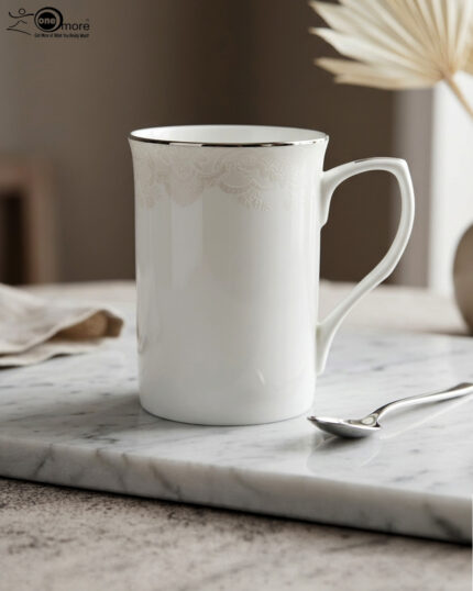 A set of two white bone china mugs on a wooden surface, one short and one tall, featuring elegant gold lace patterns and metallic gold rims against a neutral background.