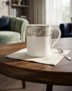 Set of two white bone china mugs from 3.jpg on a wooden table with a green placemat; one tall mug and one short mug, both featuring a grey marble pattern band and silver trim against a library background with cinematic lighting