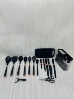 A comprehensive 17-piece kitchen tool set featuring black and rose gold silicone utensils, a matching knife set with marble-patterned handles, a vegetable peeler, kitchen shears, and a black cutting board, all stored in a clear geometric textured organizer.