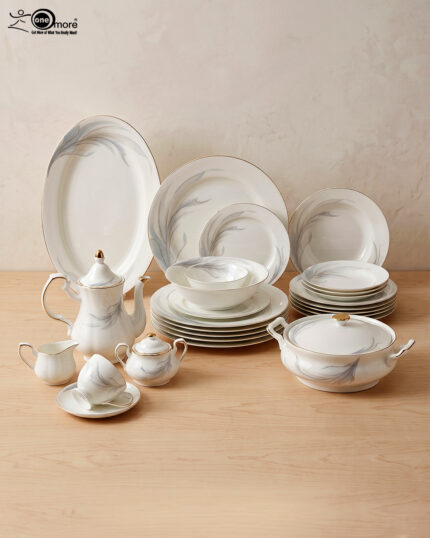 An elegant white super bone china dinner set with gold rims and a delicate grey leaf pattern, displayed on a wooden table