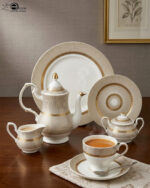 An elegant super bone china dinnerware set featuring a fine beige and gold-lined sunburst pattern, arranged neatly on a wooden table. The collection includes dinner plates, an oval platter, a tureen with a lid, soup bowls, a teapot, a creamer, a sugar bowl, and a teacup with a saucer