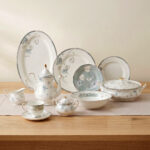 A complete super bone china dinner set featuring delicate blue and grey floral patterns with silver rims, arranged on a wooden table.