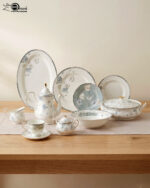 A complete super bone china dinner set featuring delicate blue and grey floral patterns with silver rims, arranged on a wooden table.