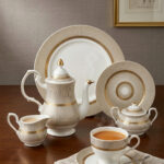 A premium super bone china tea set featuring a teapot, teacup and saucer, creamer, and sugar bowl with elegant beige striped patterns and luxury gold accents on a wooden table.