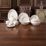 A luxurious white Super Bone China dinner set featuring delicate grey leaf patterns and gold-rimmed detailing, including plates, bowls, a teapot, and a tureen.