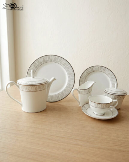 A complete 24-piece luxury tea set on a wooden table, featuring a white porcelain teapot, milk jug, sugar pot, cups, saucers, and plates with delicate silver fern patterns.